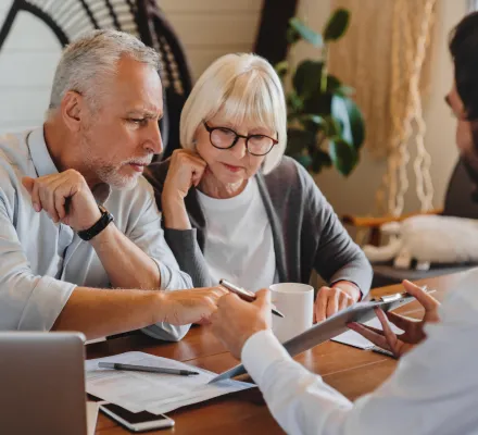 Elderly couple consulting with a professional over documents.